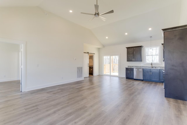 unfurnished living room with light wood finished floors, a healthy amount of sunlight, and a barn door