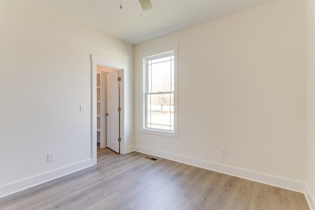 spare room featuring ceiling fan, visible vents, baseboards, and light wood-style flooring