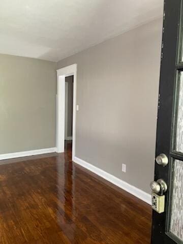 unfurnished room with baseboards and dark wood-style flooring