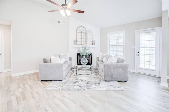 living room featuring visible vents, ceiling fan, baseboards, vaulted ceiling, and wood finished floors