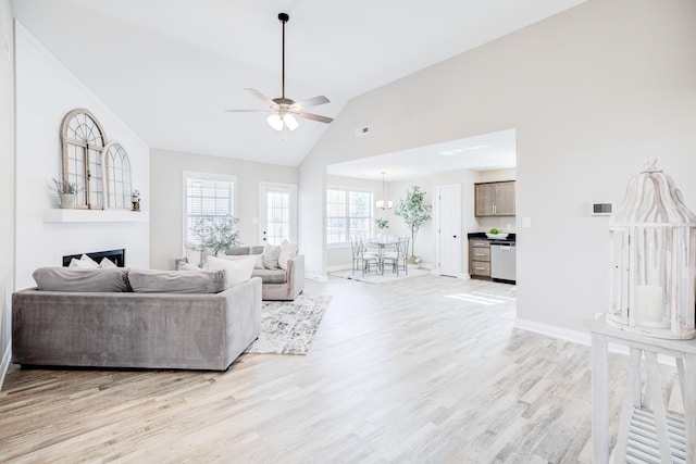 living area featuring light wood-type flooring, visible vents, baseboards, ceiling fan, and vaulted ceiling