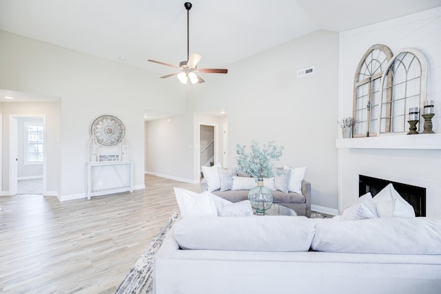 living area with a ceiling fan, wood finished floors, visible vents, baseboards, and a fireplace