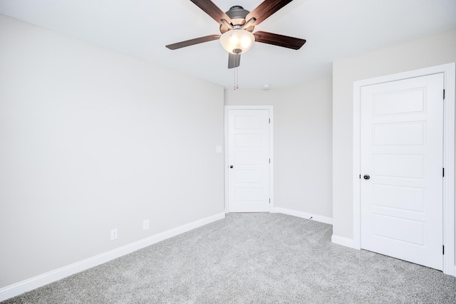 carpeted empty room featuring a ceiling fan and baseboards