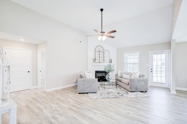 unfurnished living room with baseboards, lofted ceiling, a fireplace, wood finished floors, and a ceiling fan