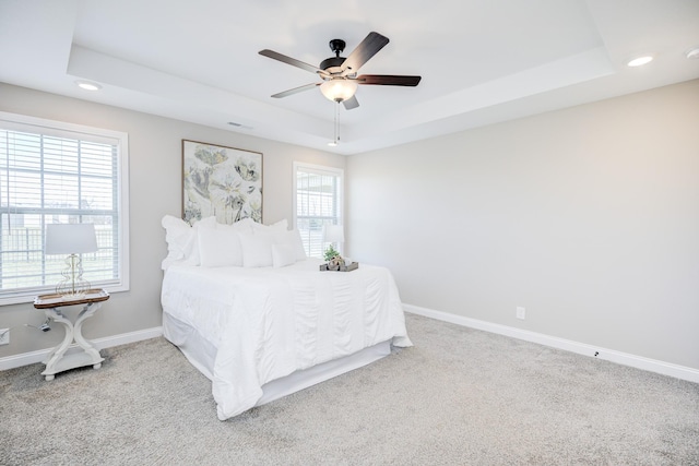 carpeted bedroom featuring a tray ceiling, recessed lighting, baseboards, and ceiling fan