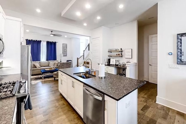 kitchen with a ceiling fan, wood finished floors, stainless steel appliances, a sink, and open floor plan