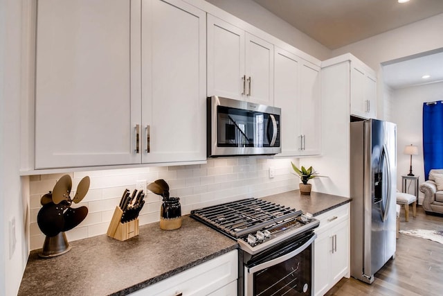 kitchen with tasteful backsplash, recessed lighting, appliances with stainless steel finishes, wood finished floors, and white cabinets