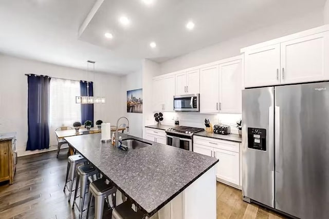 kitchen featuring a sink, stainless steel appliances, wood finished floors, and white cabinets