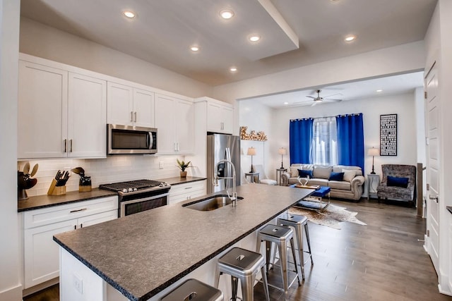 kitchen featuring tasteful backsplash, a center island with sink, a breakfast bar area, appliances with stainless steel finishes, and a sink