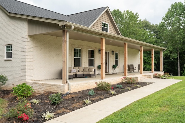 exterior space with outdoor lounge area, a patio, brick siding, and roof with shingles