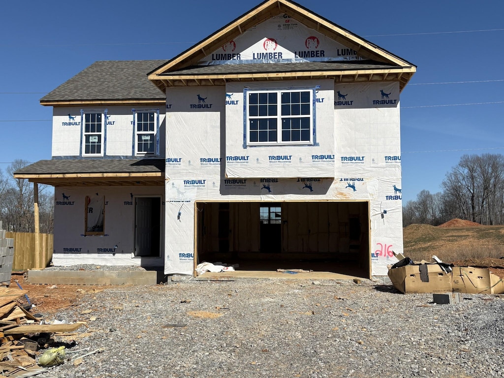 property in mid-construction with gravel driveway, a garage, and roof with shingles