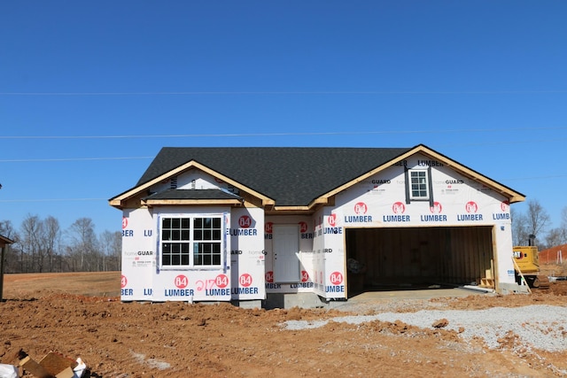 unfinished property featuring an attached garage and roof with shingles