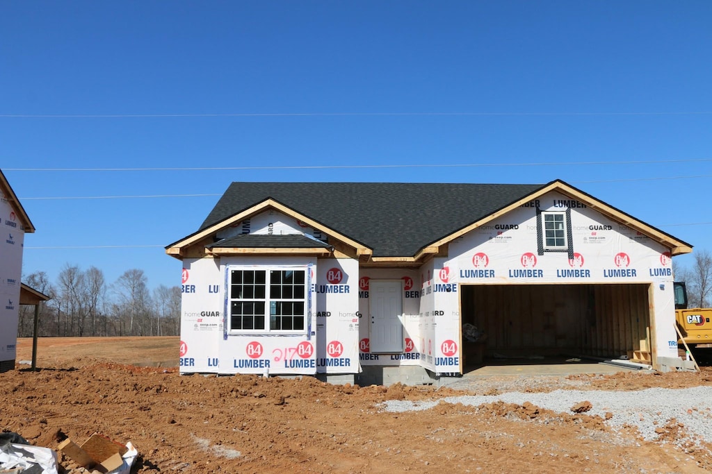 property under construction featuring an attached garage and roof with shingles