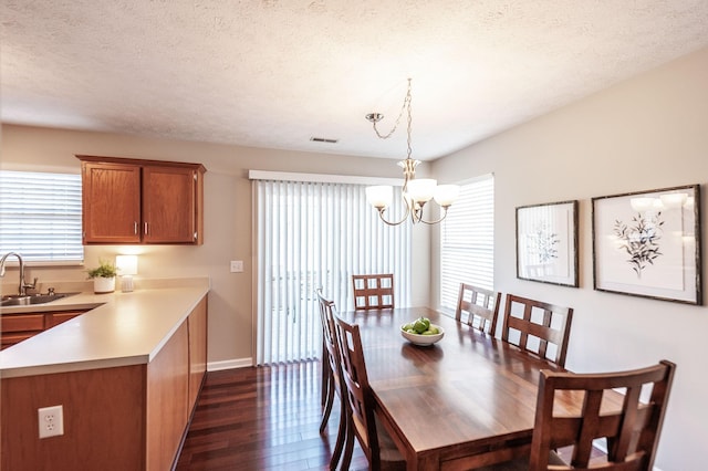 dining space featuring visible vents, baseboards, a chandelier, dark wood-style floors, and a textured ceiling