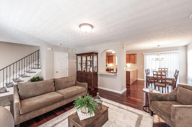 living area featuring stairway, baseboards, arched walkways, dark wood-type flooring, and a textured ceiling