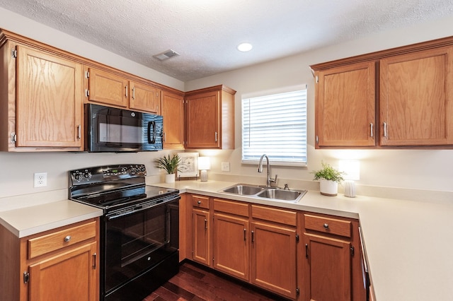 kitchen featuring dark wood-style flooring, a sink, black appliances, light countertops, and a textured ceiling