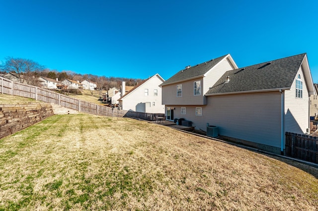 view of yard featuring a residential view, central AC unit, and a fenced backyard