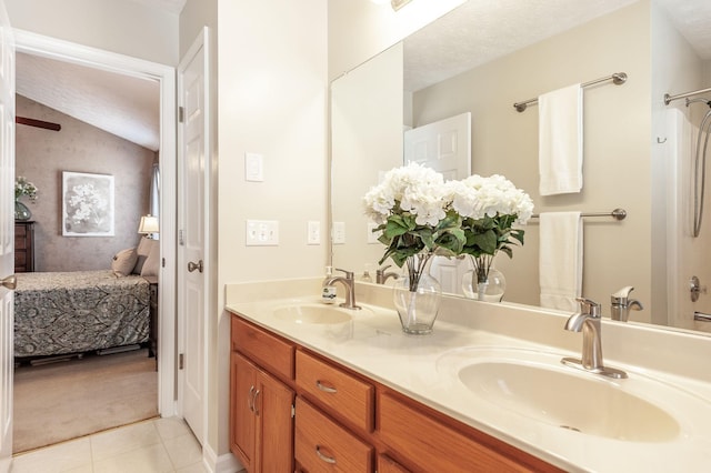 ensuite bathroom with a sink, connected bathroom, double vanity, and vaulted ceiling