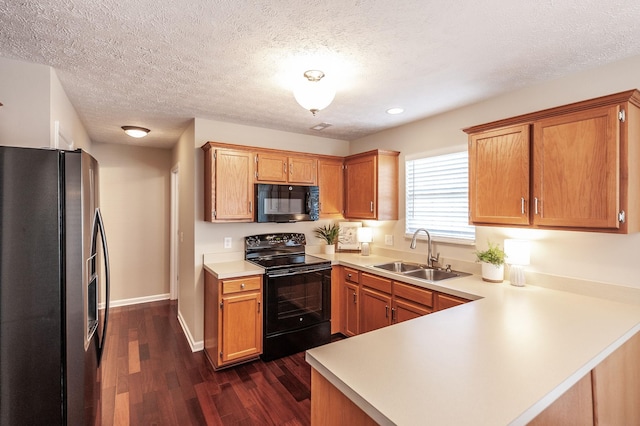 kitchen with dark wood-type flooring, black appliances, a sink, a peninsula, and light countertops