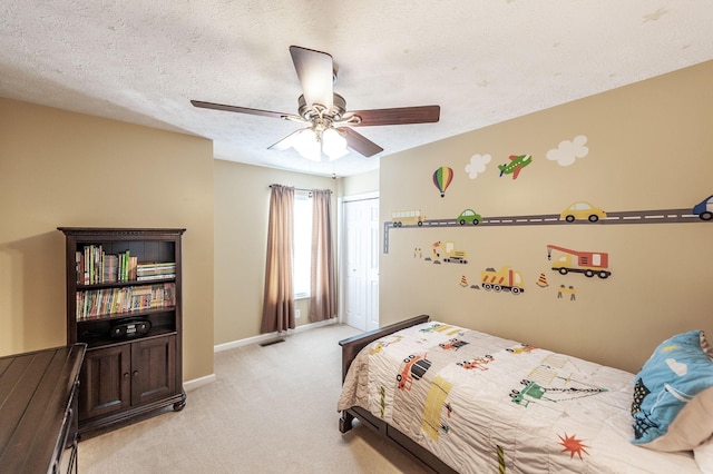 bedroom featuring light carpet, a ceiling fan, a textured ceiling, a closet, and baseboards