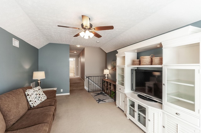 living room with baseboards, lofted ceiling, light carpet, a textured ceiling, and a ceiling fan