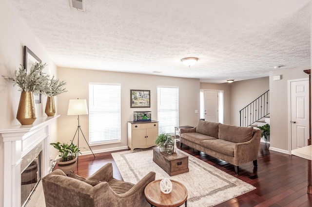 living room featuring stairway, baseboards, visible vents, dark wood finished floors, and a tile fireplace