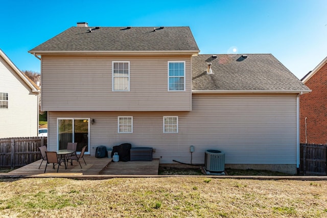 rear view of property featuring cooling unit, a lawn, fence, and a shingled roof