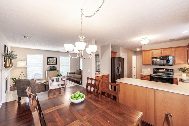 dining space featuring visible vents, dark wood-type flooring, a notable chandelier, and a textured ceiling