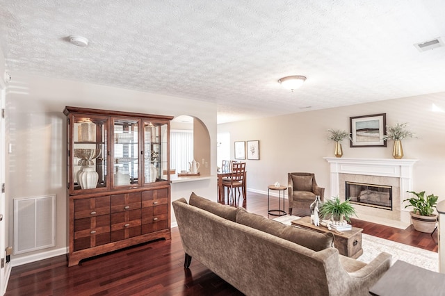 living room with dark wood finished floors, visible vents, a textured ceiling, and a premium fireplace