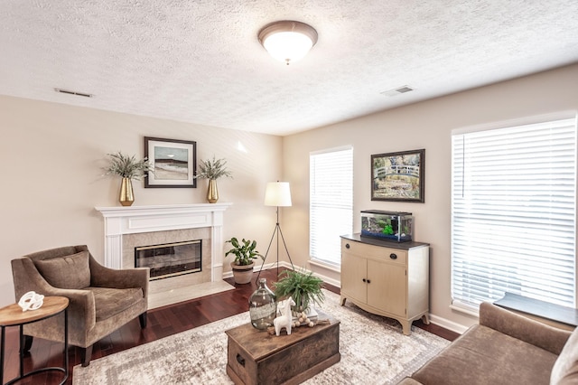 living area featuring wood finished floors, a fireplace, visible vents, and baseboards