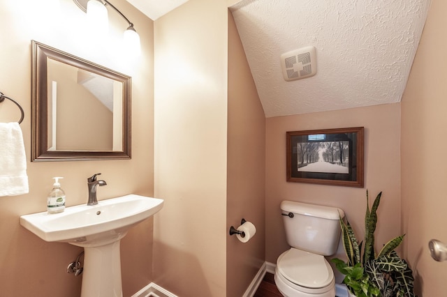 half bathroom featuring baseboards, visible vents, lofted ceiling, a textured ceiling, and toilet