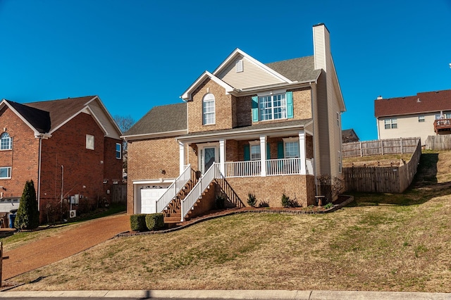 traditional home featuring stairway, covered porch, a garage, brick siding, and a chimney