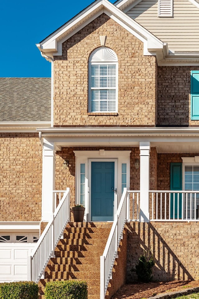 entrance to property featuring brick siding and covered porch