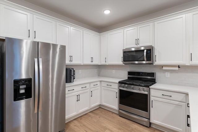 kitchen featuring decorative backsplash, light countertops, light wood finished floors, and appliances with stainless steel finishes