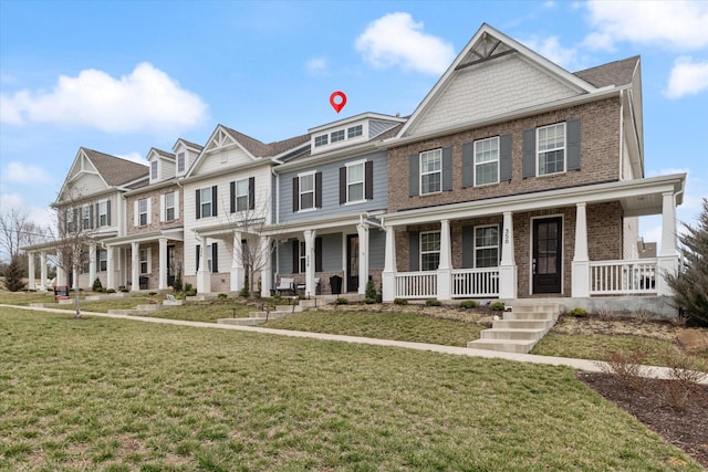 multi unit property with brick siding, a porch, and a front yard