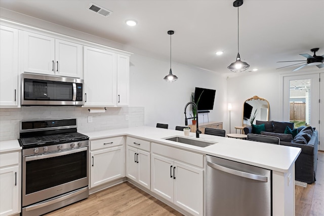 kitchen with visible vents, a peninsula, a sink, stainless steel appliances, and open floor plan