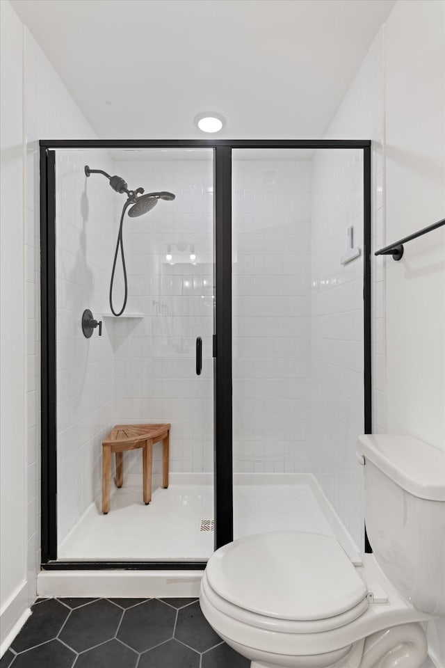 bathroom featuring tile patterned floors, toilet, and a stall shower