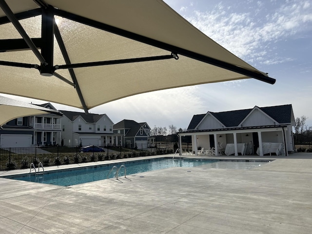 pool with a patio area, fence, and a residential view