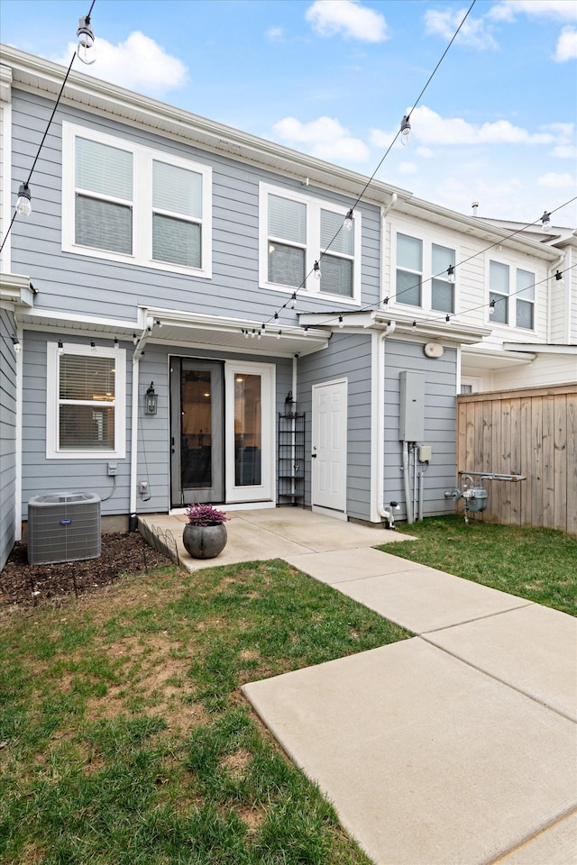 rear view of house featuring a patio area, central air condition unit, a lawn, and fence