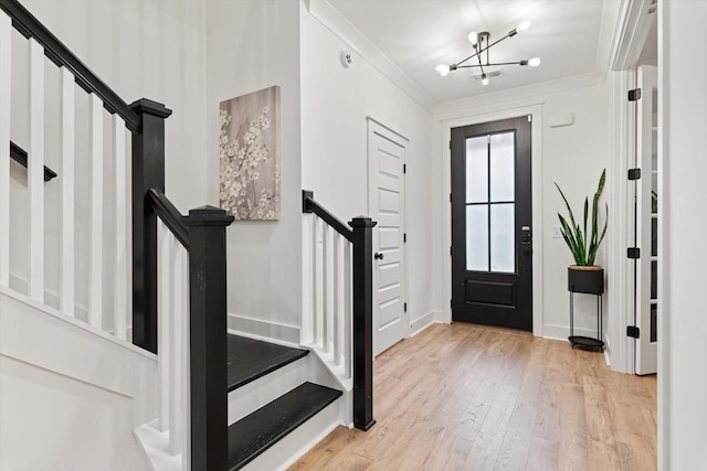 foyer entrance featuring crown molding, baseboards, a chandelier, stairway, and hardwood / wood-style floors