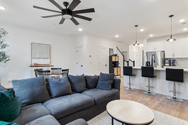 living room featuring recessed lighting, light wood-type flooring, ornamental molding, and a ceiling fan