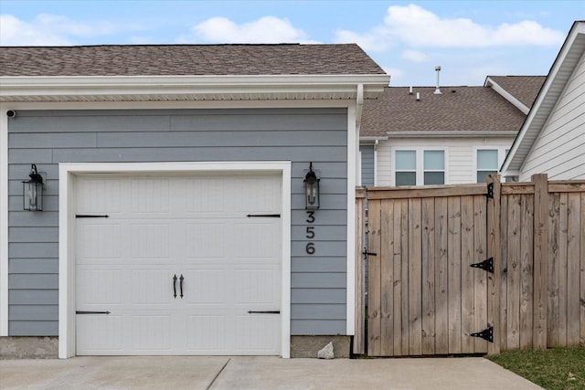 garage with concrete driveway and fence