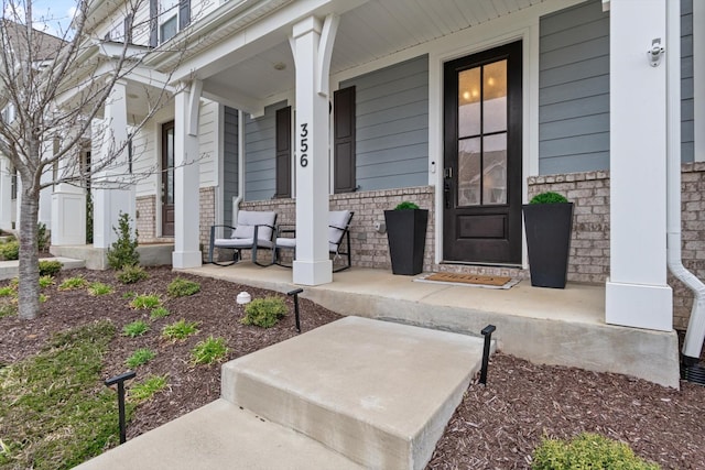 view of exterior entry featuring stone siding and a porch