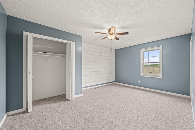 11216 Clay County Hwy, Moss, TN 38575 - unfurnished bedroom featuring a ceiling fan, a textured ceiling, a closet, wooden walls, and carpet