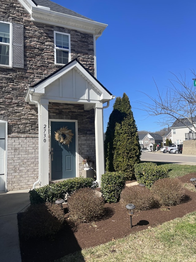 view of exterior entry featuring board and batten siding and stone siding