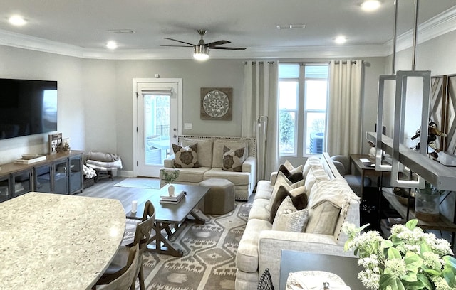 living area with baseboards, a ceiling fan, wood finished floors, and crown molding