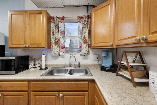 kitchen featuring stainless steel microwave, light countertops, and a sink