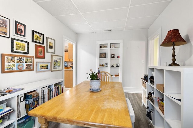 dining room featuring a drop ceiling, visible vents, and dark wood-style flooring