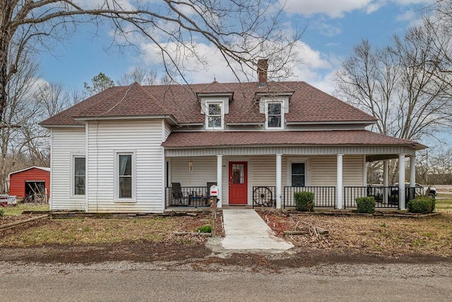 view of front of property featuring a porch, a chimney, and a shingled roof