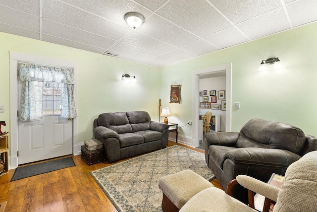 living area with visible vents, a drop ceiling, baseboards, and wood finished floors